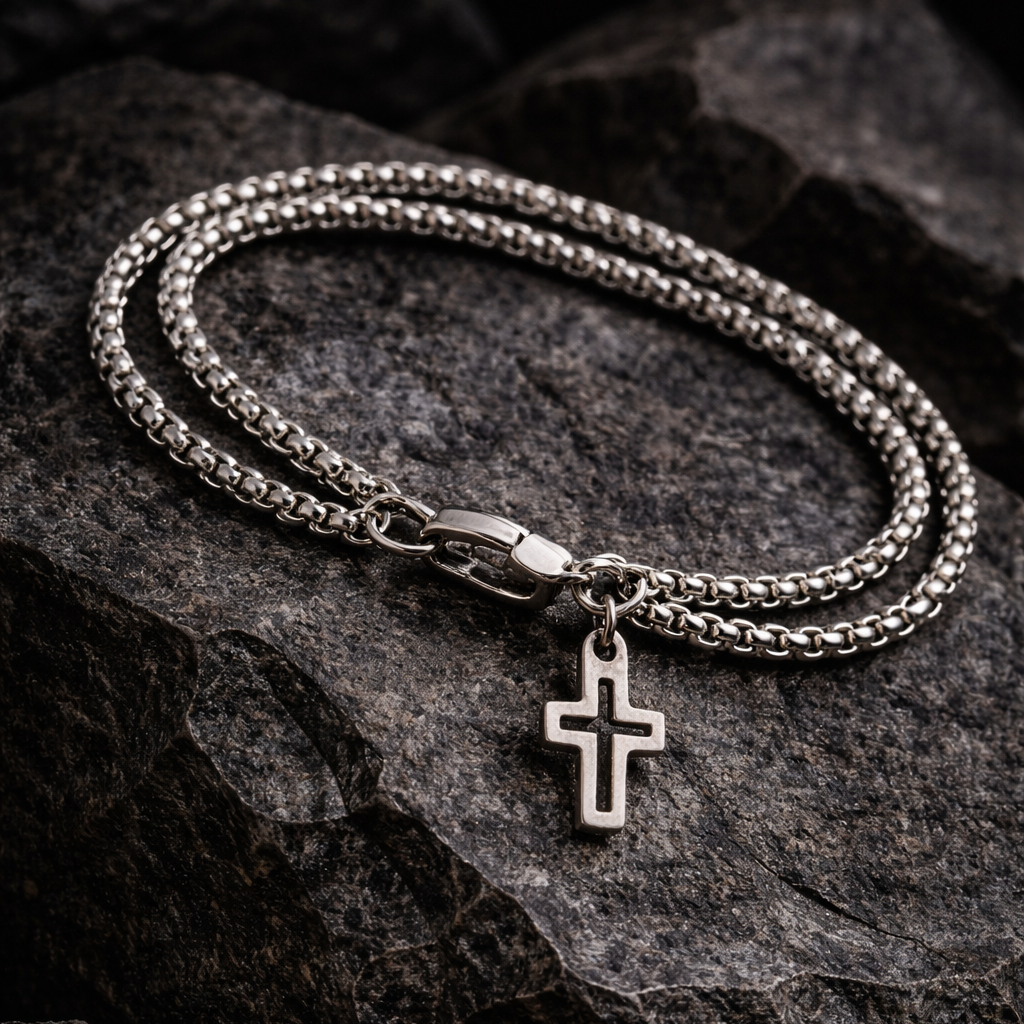 Silver chain bracelet with a cross pendant on a dark stone surface