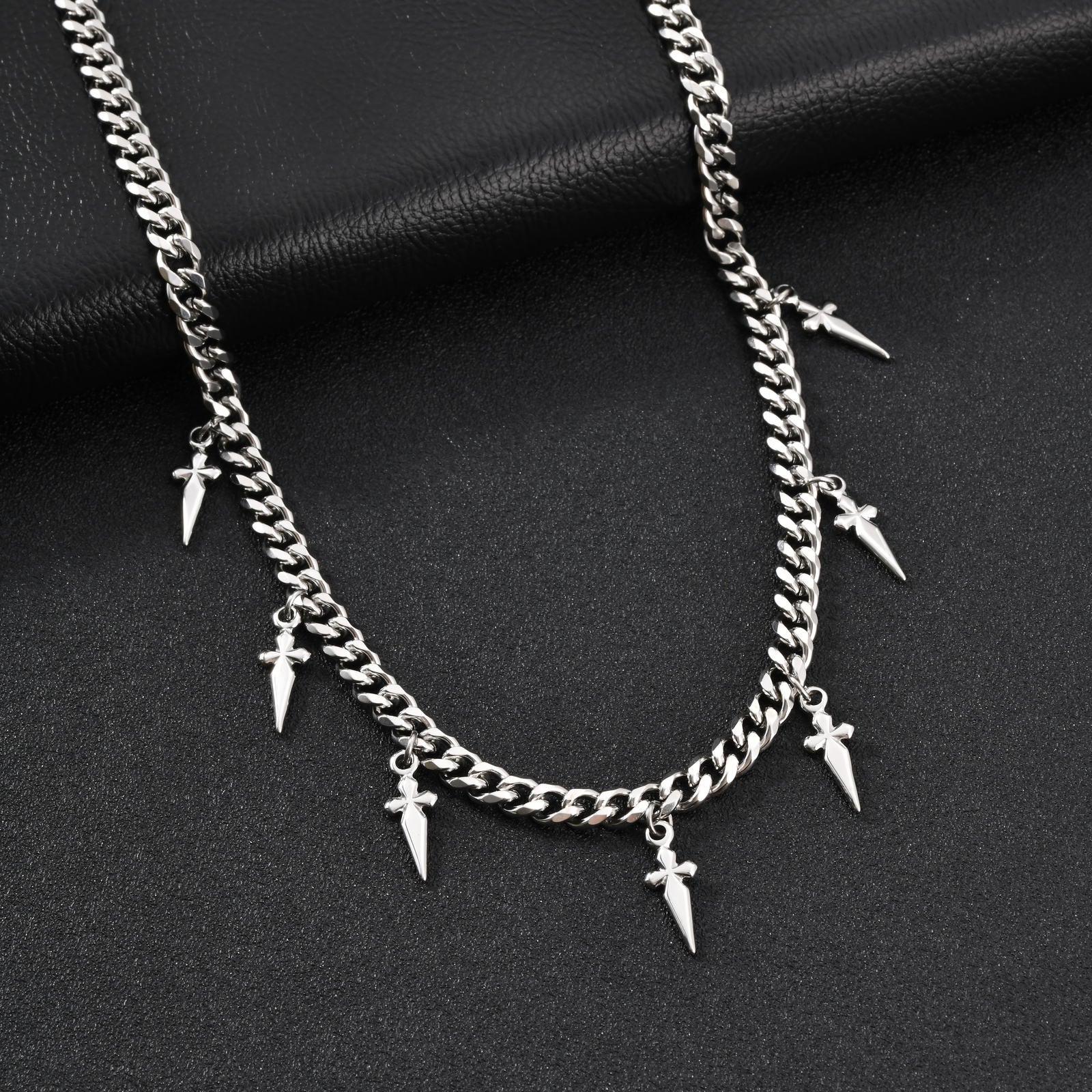 Silver chain necklace with spike-like pendants on a black background