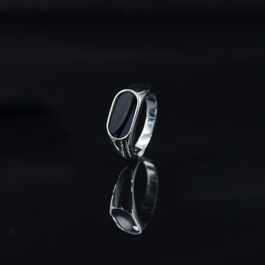 Silver ring with a black stone on a black background