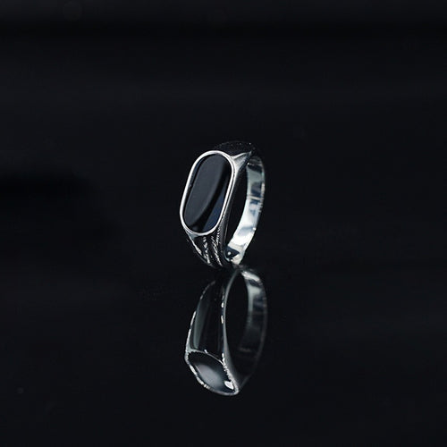 Silver ring with a black stone on a black background
