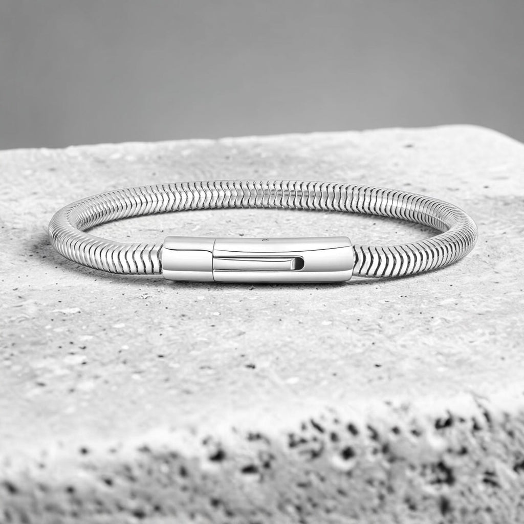 Silver bracelet on a textured stone surface with a gray background