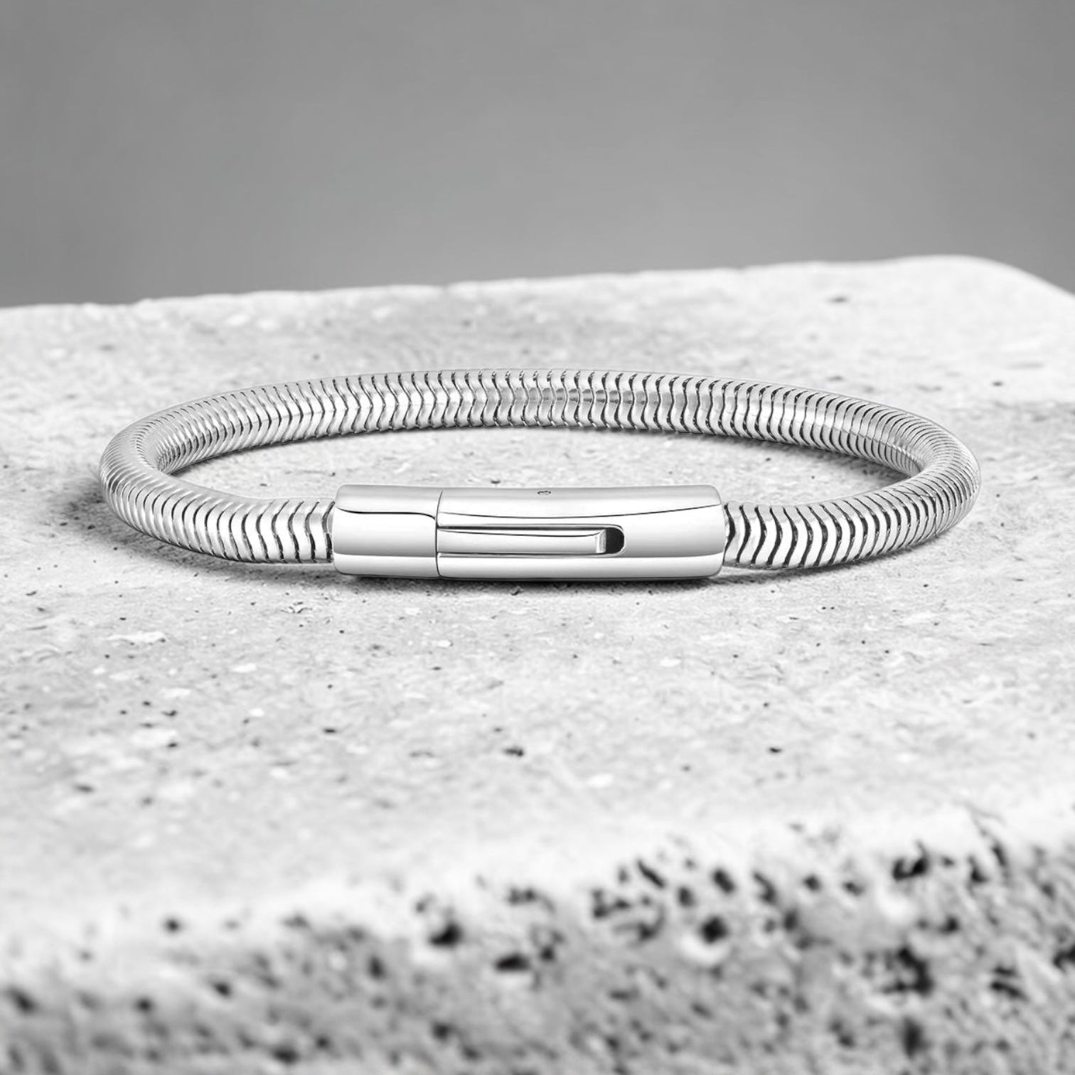 Silver bracelet on a textured stone surface with a gray background