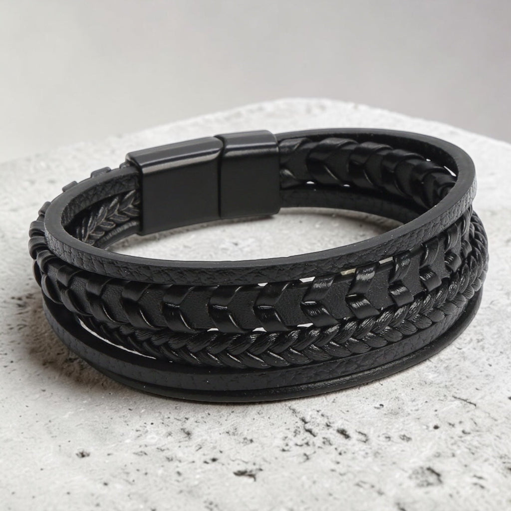 Black braided leather bracelet on a light gray surface