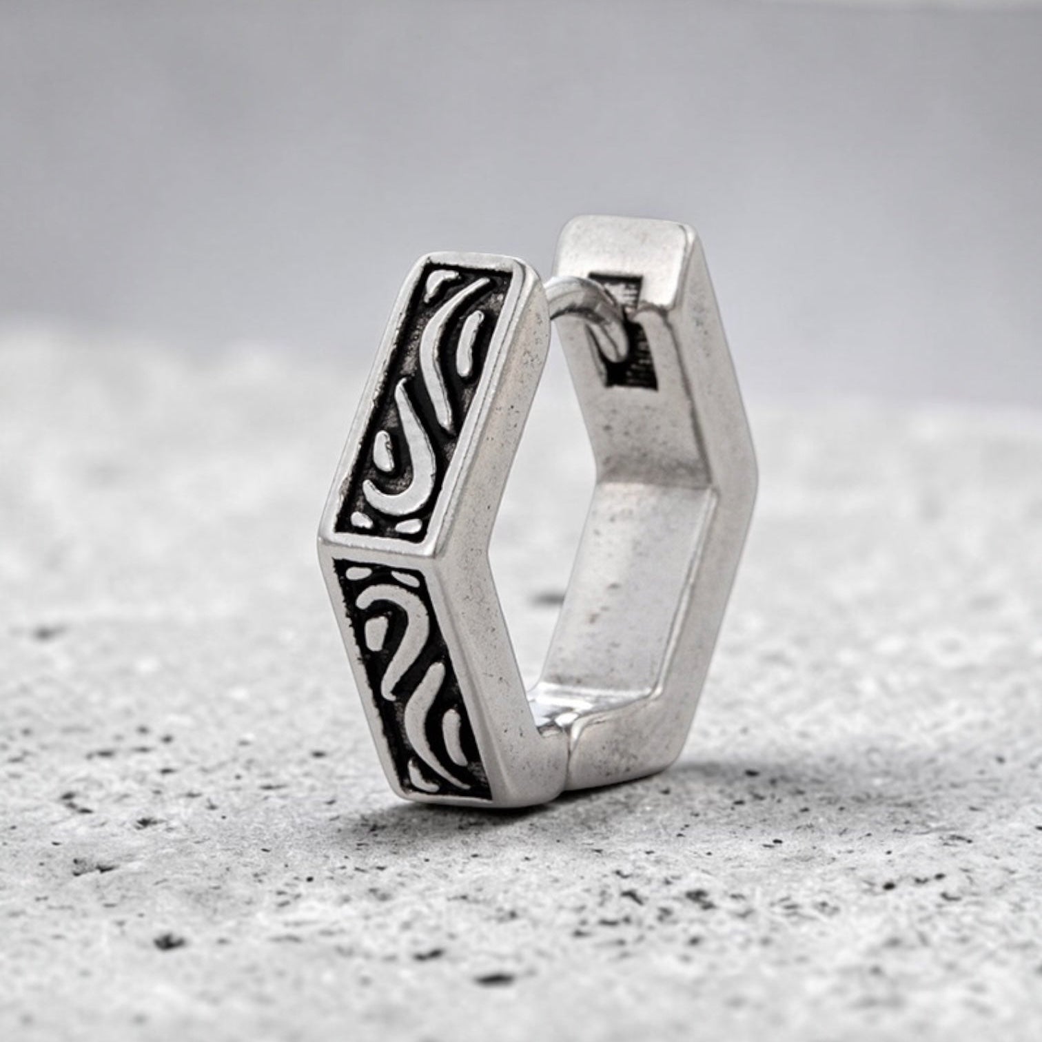 Silver hexagonal hoop earring with intricate design 