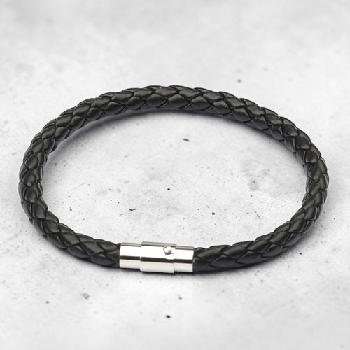 Black braided leather bracelet with a silver clasp on a light gray background