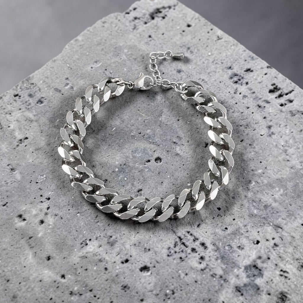 Silver chain bracelet on a textured stone surface with a gray background