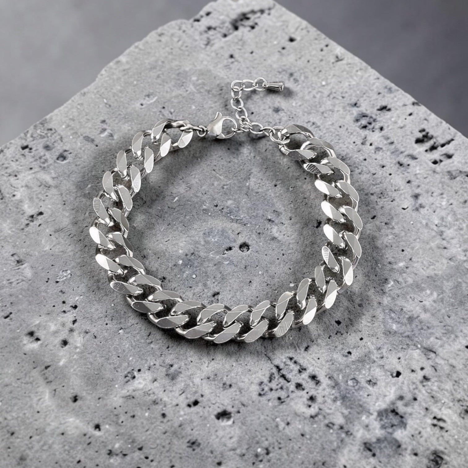 Silver chain bracelet on a textured stone surface with a gray background