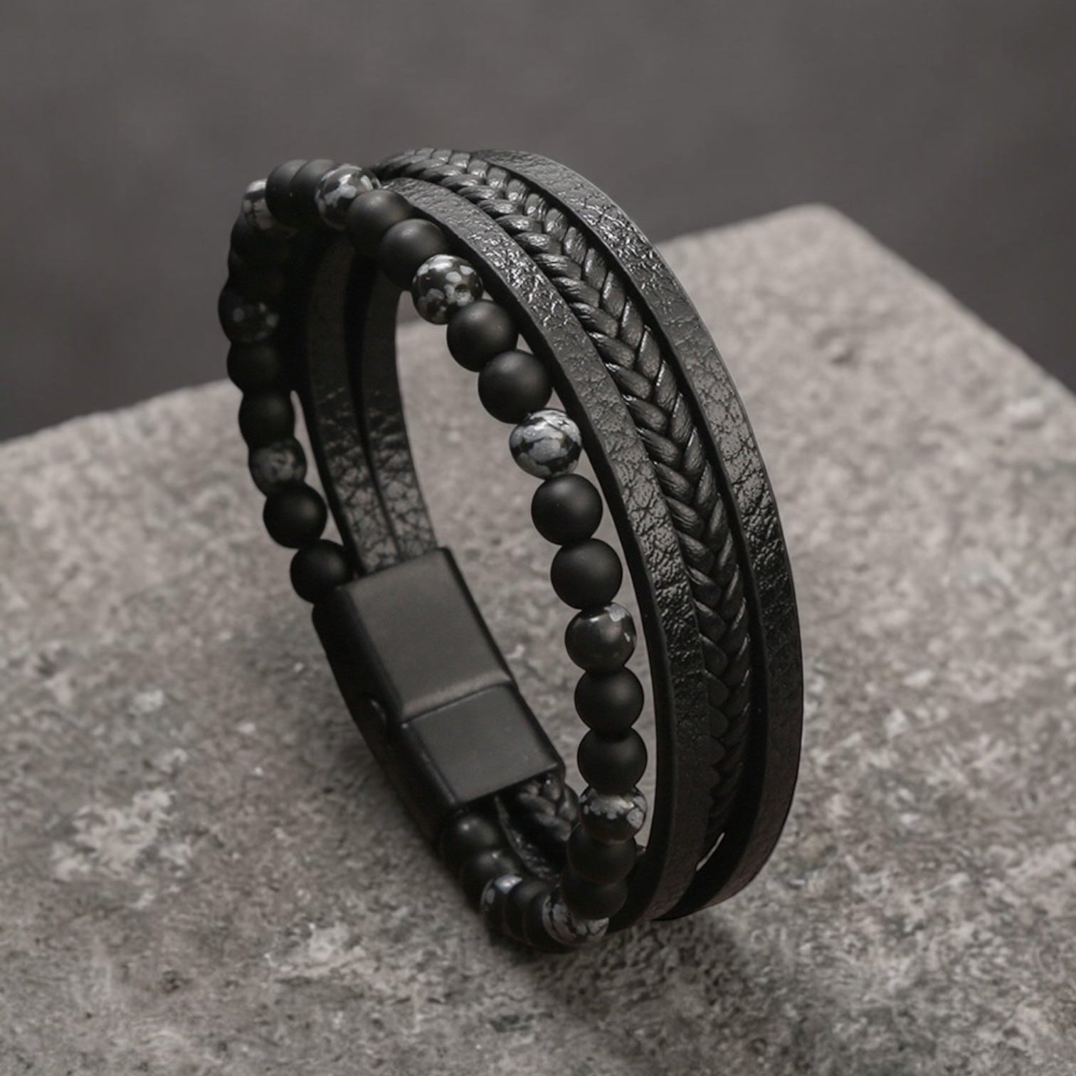 Black leather and beaded bracelet on a textured stone surface