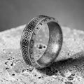 Silver ring with intricate designs on a textured surface